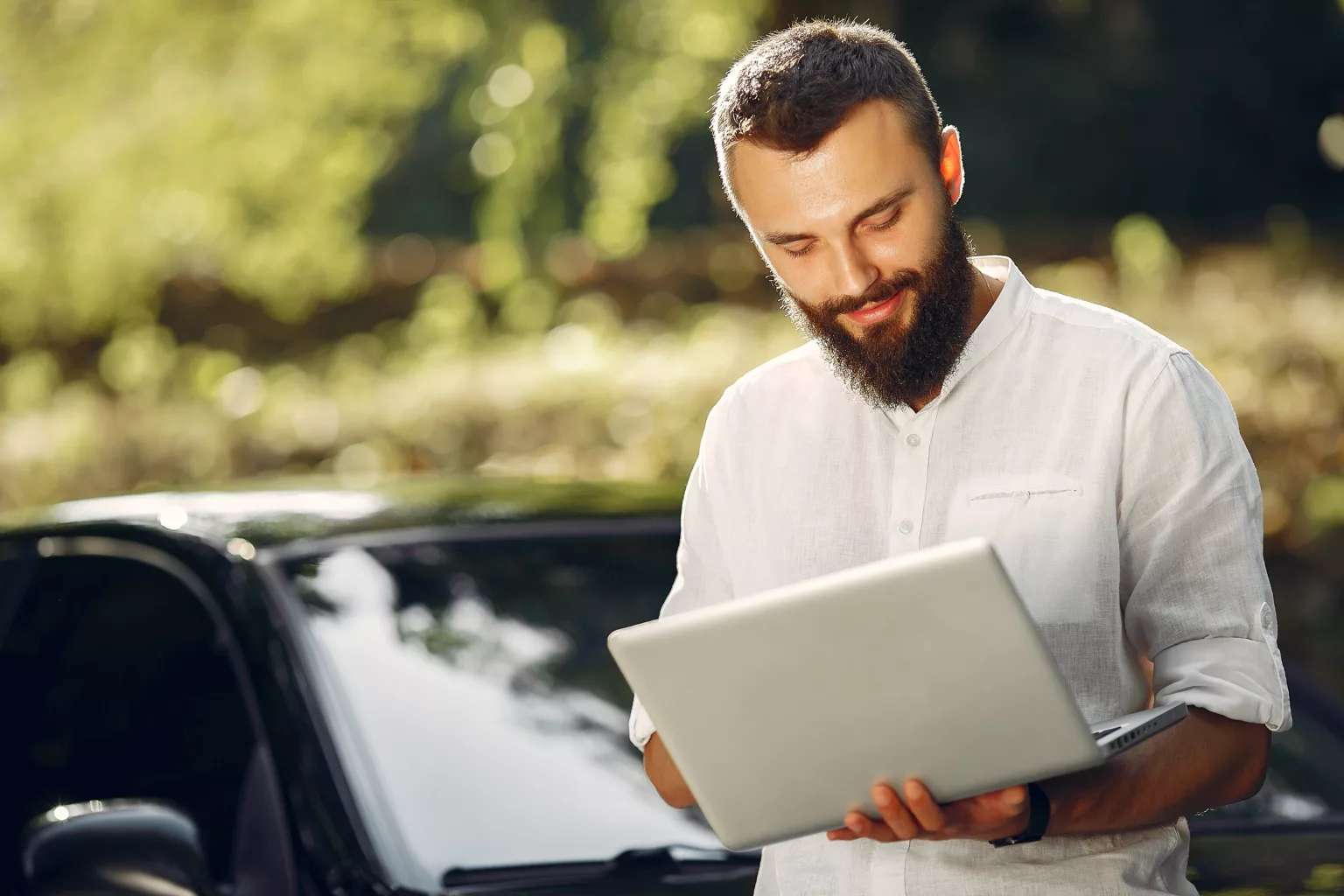 Handsome man in a white shirt. Businessman working with laptop. Man standing near a car